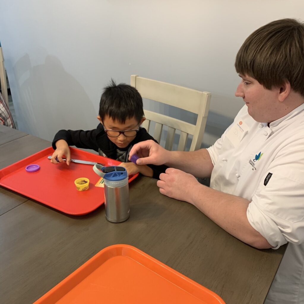 Dillon is helping Tian Ai as he participates in Kids in the Kitchen.