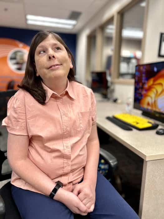 Sara is seated in our technology center where clients learn about adaptive technology.