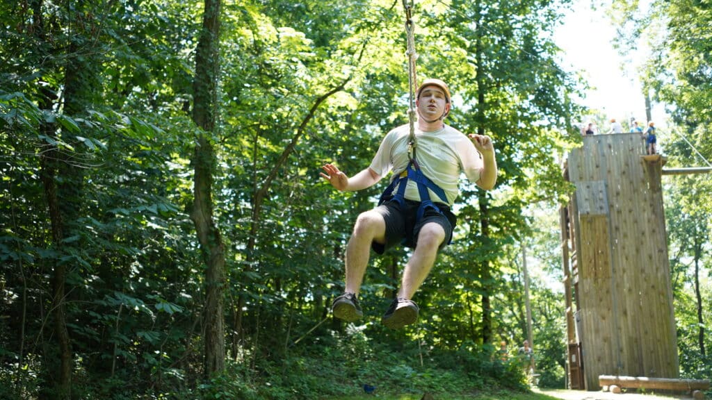 A camper is hurtling through the air on a zipline.