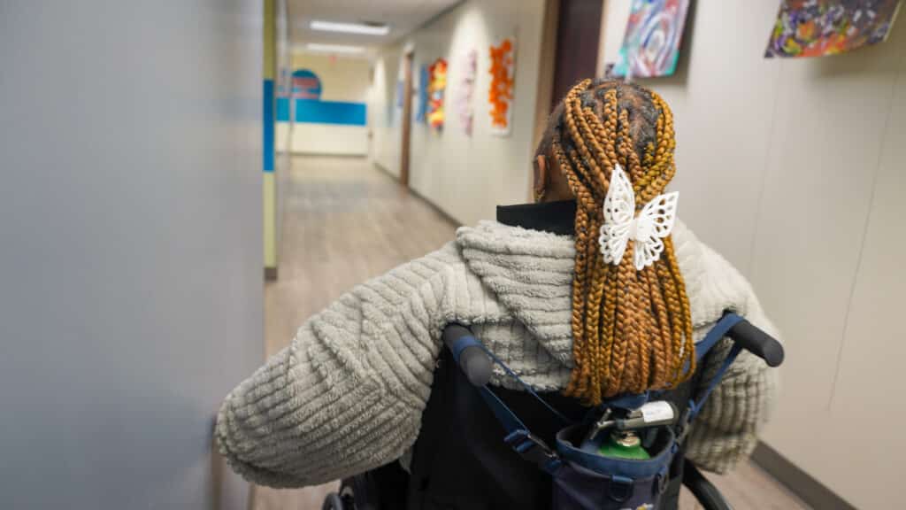 Tara is moving down the hallway at Alphapointe. This image was taken from behind her as she navigates using the wall. 