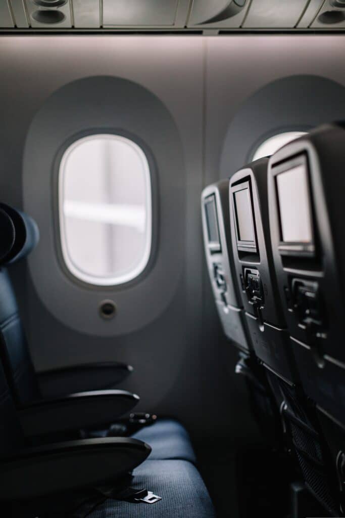 This is a black and white image of an empty row of seats on an airplane.