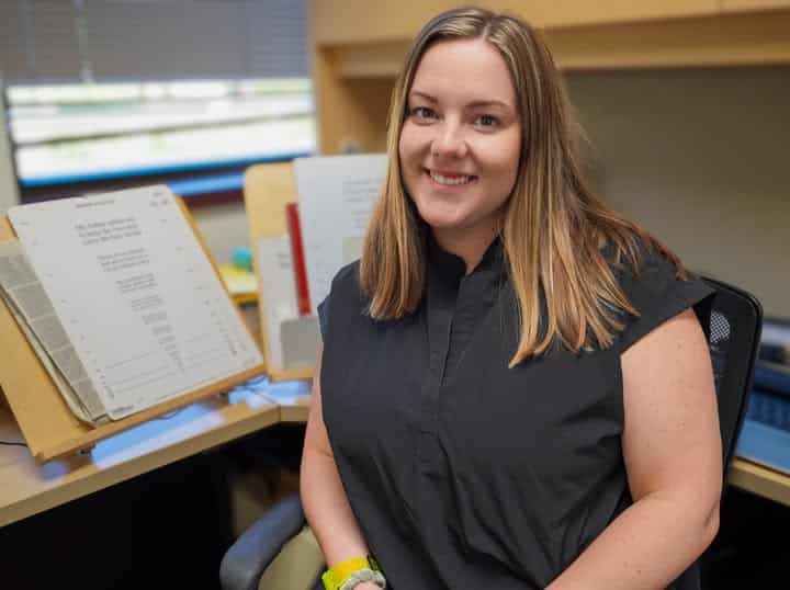 Shannon is seated at a desk and is smiling at the camera.
