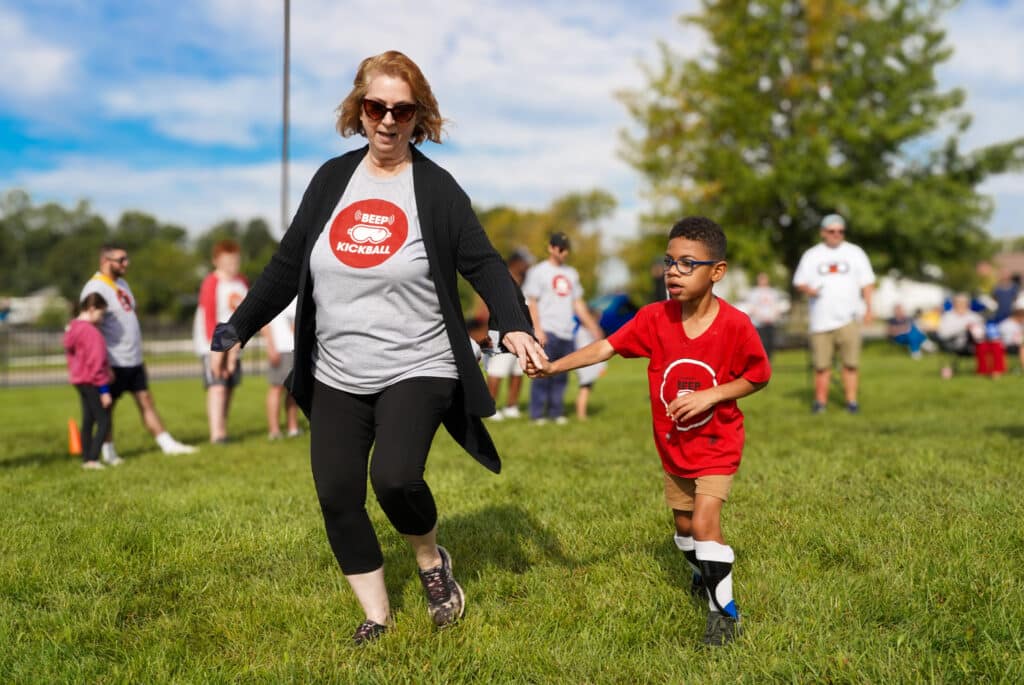 During Beep Kickball, volunteers help guide players toward the bases.