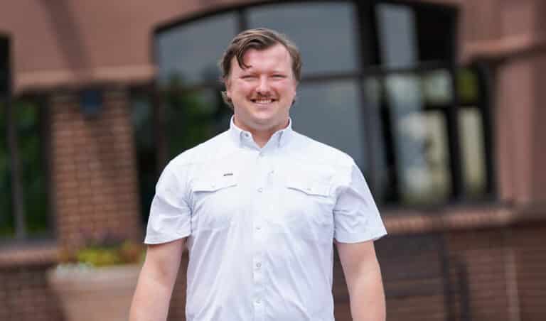 Jason is standing outside of the Alphapointe building and is smiling at the camera.