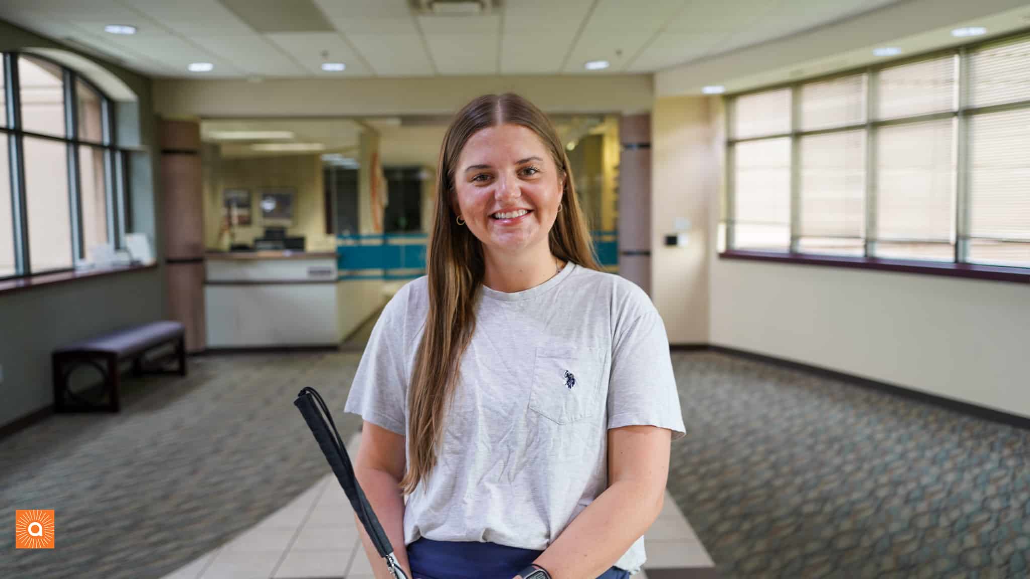 Riley is standing in the Alphapointe lobby and is smiling at the camera.